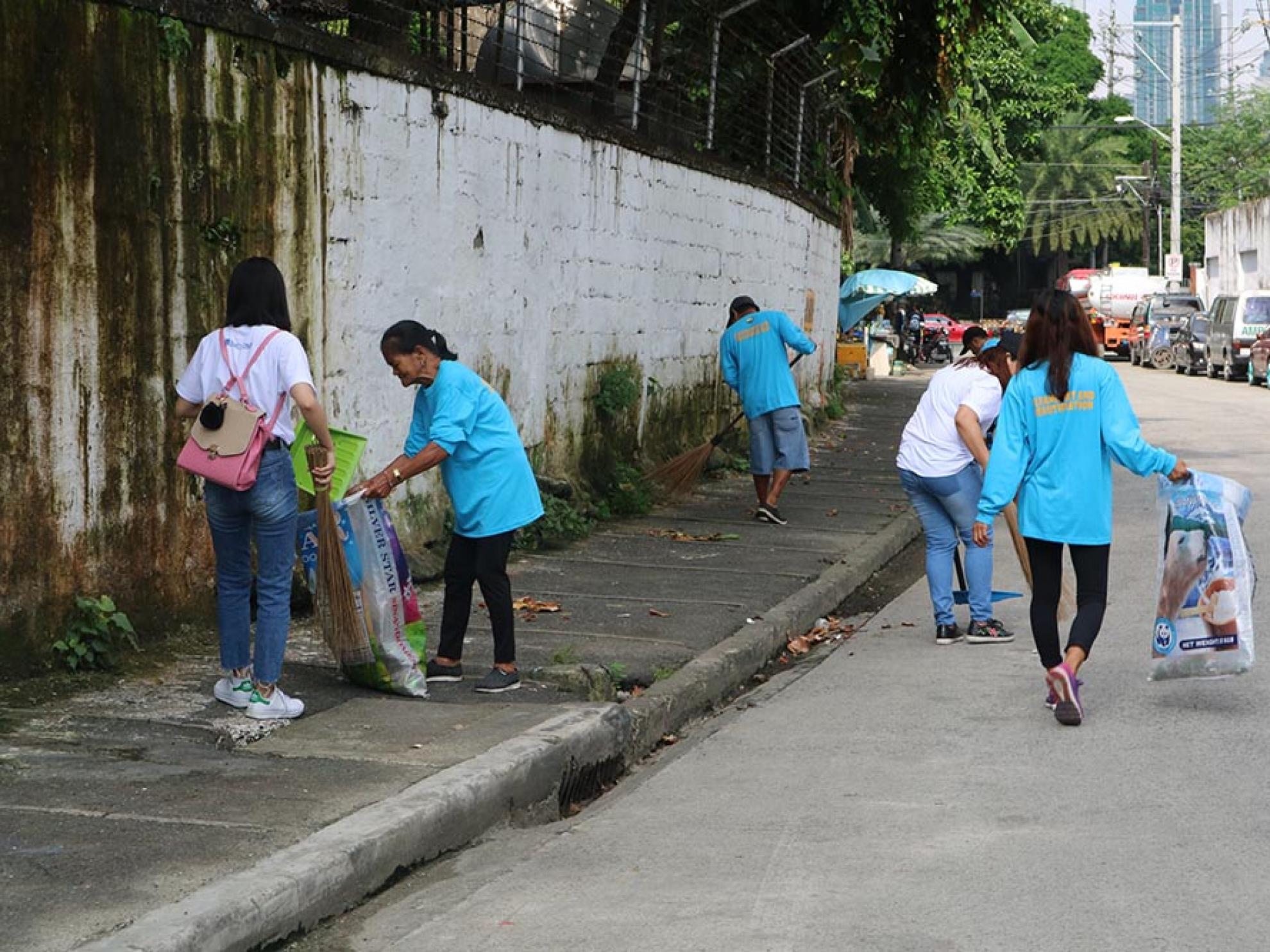 DMCI volunteers working with members of Barangay Guadalupe Viejo’s clean and green committee.
